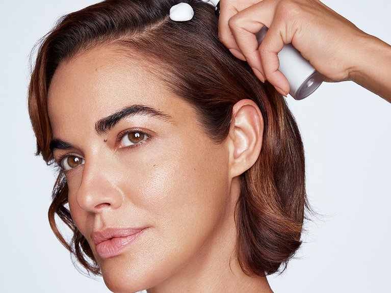 Woman applying Volumizing Enhancing Foam to scalp