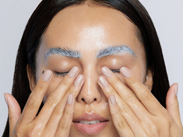 woman rinsing masque off lashes and brows