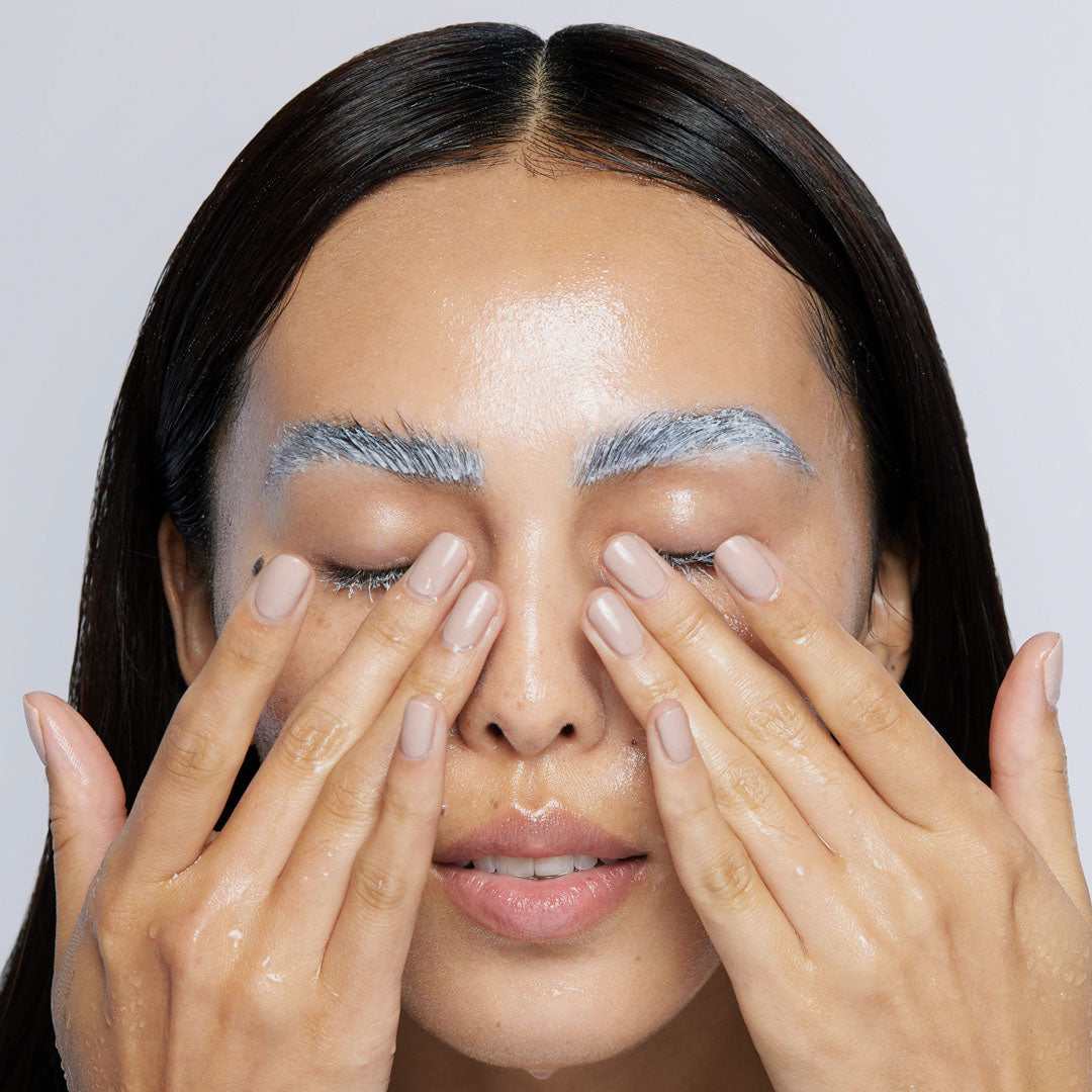 woman rinsing masque off lashes and brows