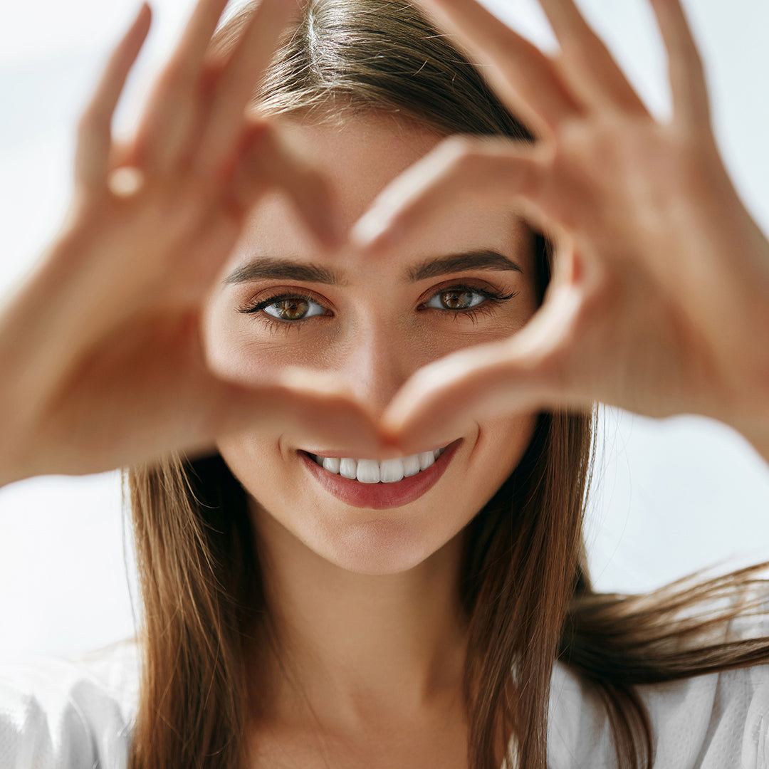 Image of woman looking through her fingers that she shaped into a heart